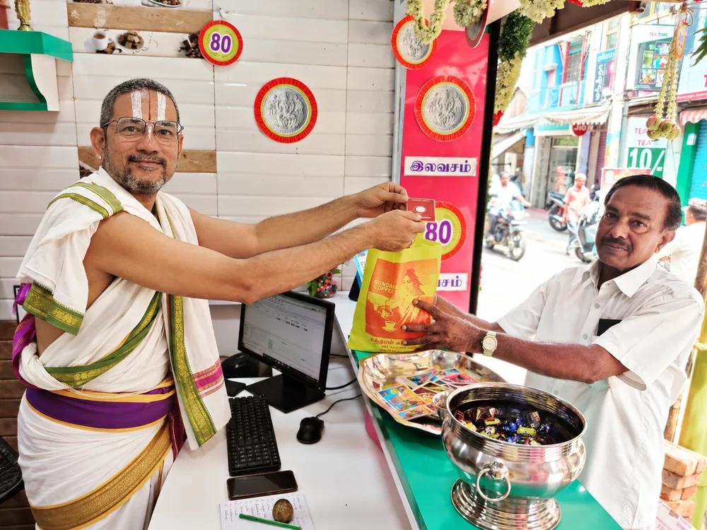 Rajagopalan N. handing a bag of coffee across his counter to a customer