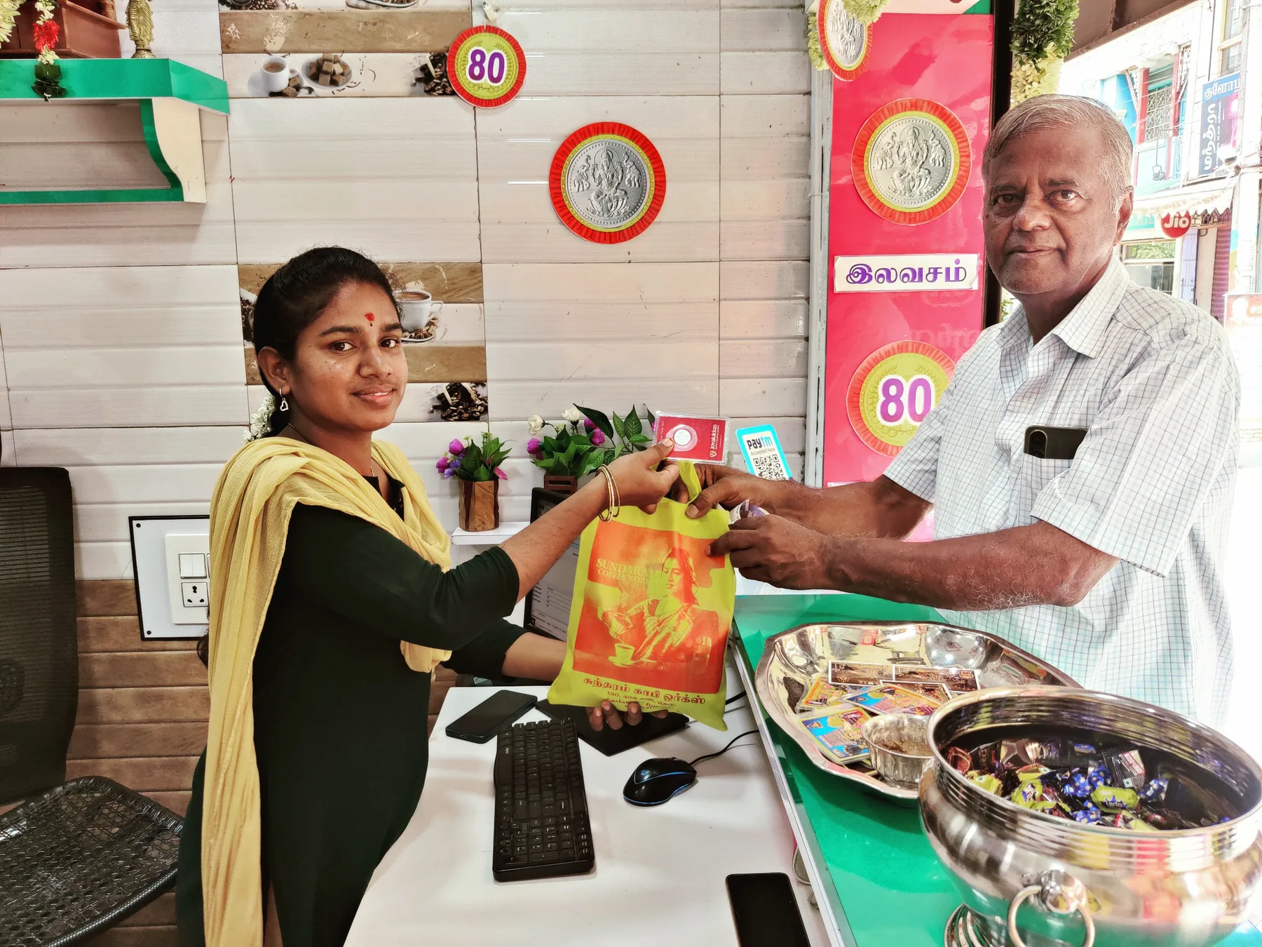 A Sundaram Coffee Works bag handed across the counter to an elderly customer